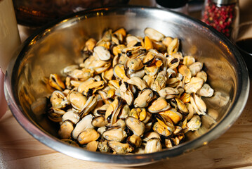 Cooked Mussels in a Large Metal Bowl. A bowl full of freshly cooked mussels, ready to be served as a delicious seafood dish in a kitchen setting.