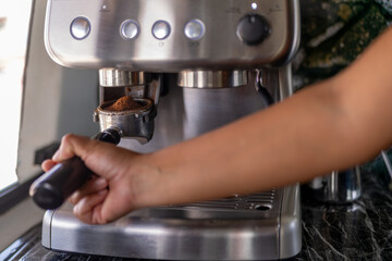 Hand on a barista preparing coffee with a machine
