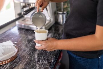 Barista pouring milk into a cup of cappuccino