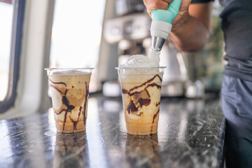 Worker adding cream to a frappe in a food truck