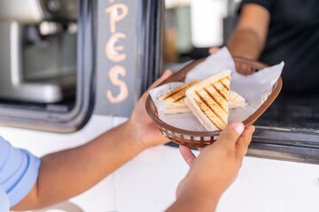 Serving a sandwich through the window of a food truck