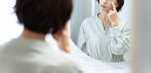 鏡を見てほうれい線を気にする日本人女性