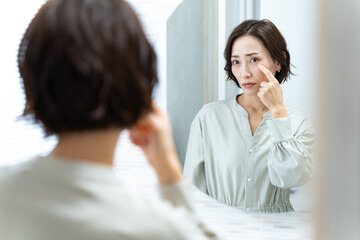 鏡を見て首を気にする日本人女性