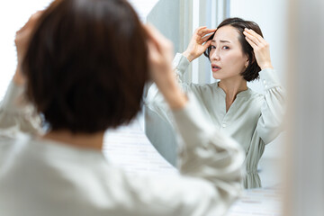 鏡を見て髪の毛を気にする日本人女性