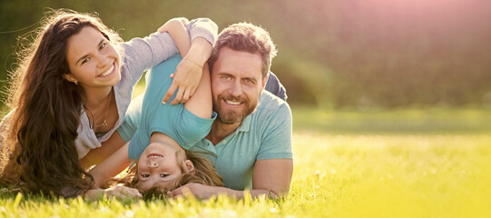 Banner of Happy family Lying on grass. Young mother and father with child son in the park resting...