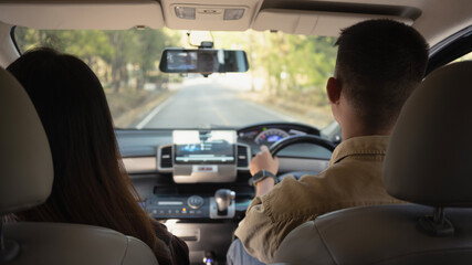 Rear view of couple having fun together driving by countryside. Road trip, traveling and lifestyle concept