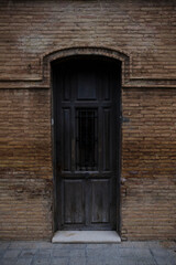 Fototapeta na wymiar Puerta antigua de madera en una fachada de ladrillo