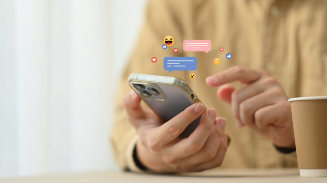 Young woman using mobile phone with likes, emoji icons while sharing or commenting in online community