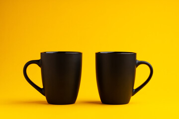 Two mugs on yellow studio background close up