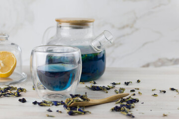 Glass cup of organic blue Anchan tea on a light foul. Herbal tea. Clitoria ternatea