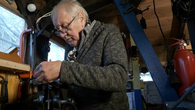 Senior mechanic uses Vernier caliper to measure machine part held in a bench vice