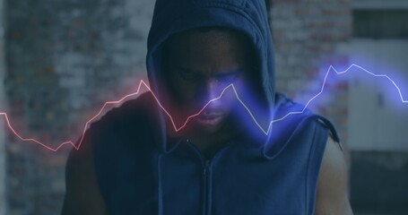 Image of colourful shapes over man wearing a hoodie in an abandoned building