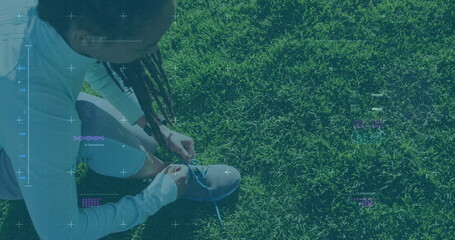 Image of statistics and graphs over woman tying her shoes on grass