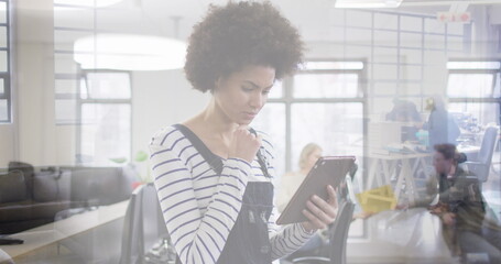 Image of biracial businesswoman with tablet over cityscape