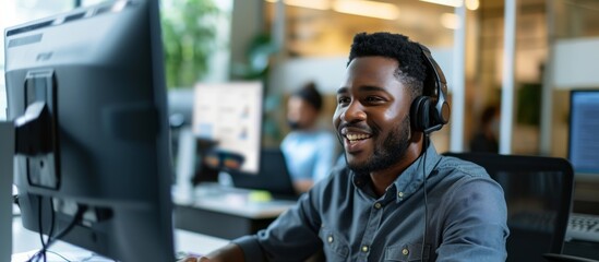 Black man working in an office offering customer service, tech support, and advice through call center, computer, and online platforms.