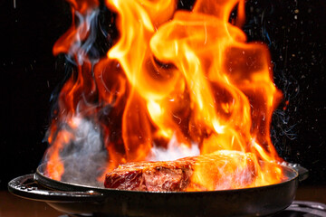 炎に包まれた調理中のサーロインステーキ
