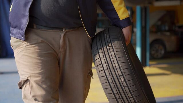 The car mechanic is changing the car tire at the car repair shop or garage.