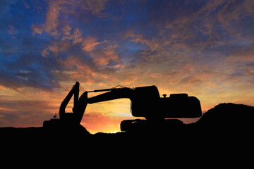 Two Crawler excavators silhouette are digging the soil in the construction site. on the sunset ...