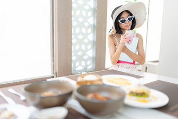 Asian female tourists come to relax Drinking sweet drinks in the hotel restaurant, holding a...