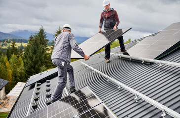 Professional technicians carrying solar PV battery. Engineers installing solar panel on a roof of...