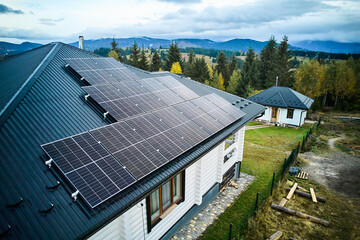 Solar panels on a top of house. Roof of solar batteries. Aerial view of white wooden house with PV...
