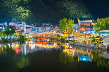 View of the lake in the ancient and touristy Chinese town of Yangshuo with reflections in the water and surrounded by the restaurants, cafes and shops of the well-known West Street (Xi Jie) at night.