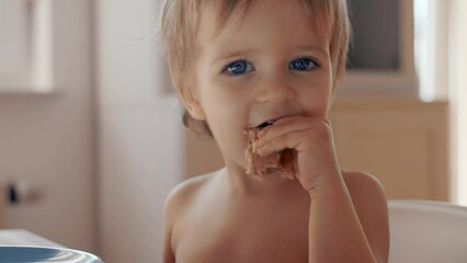 A young boy with striking blue eyes diligently Eating Pancake.