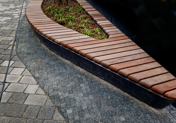 drop shaped or ellipse bench on cobbled square. the paneling of  bench seating area is made of...