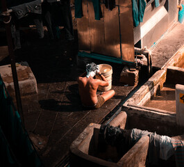 Indian man bathing in open under sunlight in a rural slum