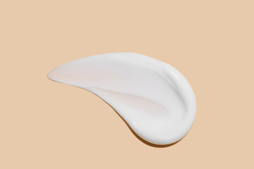 Cosmetic product smear white moisturizing lotion isolated on beige, squeezed out and smeared portion of skincare cream product testing. - obrazy, fototapety, plakaty