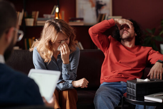 Selective focus over-the-shoulder of young married couple suffering discord crying at family therapy session