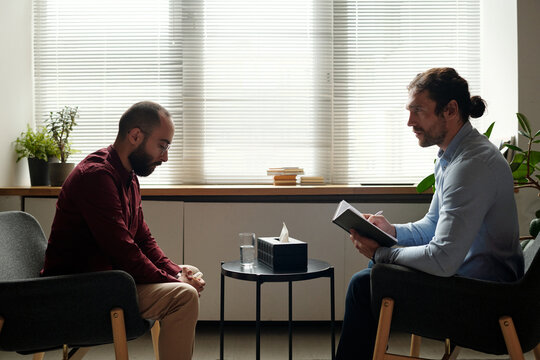 Side view shot of professional psychologist working with Middle Eastern patient suffering major depressive disorder