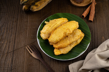 Deep fried sweet crispy banana or Pisang goreng on white plate and banana leaf
