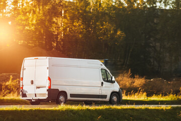A mockup of a white van with an empty wrap for you to customize. A commercial vehicle for your delivery and transport service. Isolated small white truck on the road.