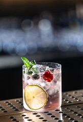 Pink cocktail Gin Tonic drink with raspberries, blueberries, lime and fresh mint