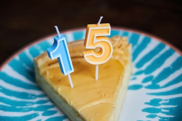 A piece of cake with the numbers 15. The fifteenth birthday. A cake on a blue plate.