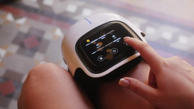 Girl athlete uses a modern massage for therapeutic relaxation of the knee. The concept of sports recovery after training and injury.