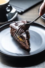 A guest in a cafe cuts a Sacher cake with a fork.