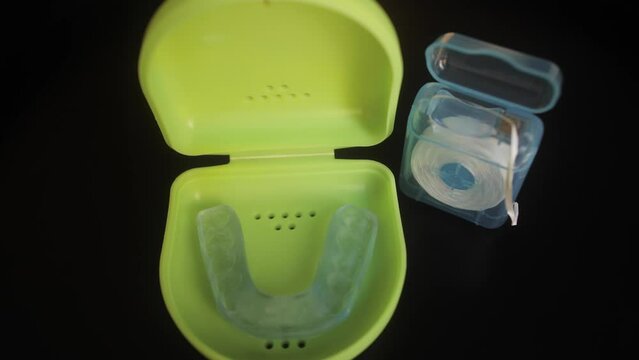 Case with mouthguard for teeth and dental floss close up. Dental care concept.
