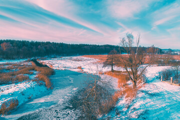 Aerial view of the countryside and frozen winding brook on a sunny day. Beautiful nature landscape