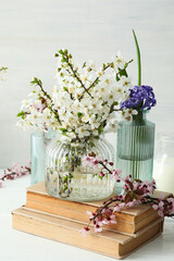 Obraz na płótnie Canvas Spring twigs with flowers in a jar, with books on a light background.