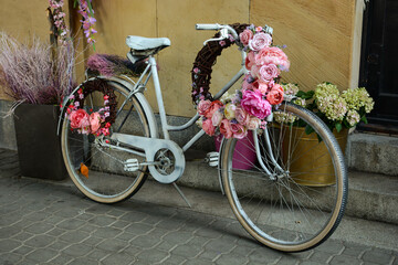 In front of the store there is a white bicycle decorated with flowers. modern decor on a city street