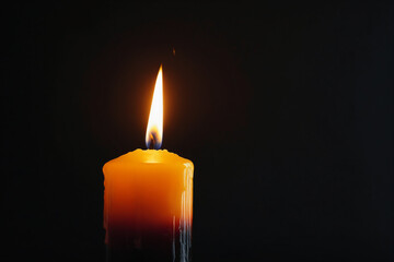 Black candle burning with streaks of paraffin on dark background