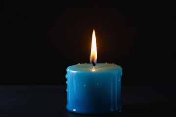 Obraz na płótnie Canvas Blue candle burning with streaks of paraffin on dark background