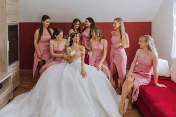 Naklejka premium A beautiful bride and her bridesmaids are having fun in the morning. Wedding celebration. Happy girls at their best friend's wedding. A beautiful and elegant bride with her bridesmaids