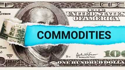 Commodities. The word Commodities in the background of the US dollar. Trading and Investment in Raw...