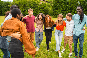 A multicultural group of young people smile and socialize in a park, a symbol of friendship and...