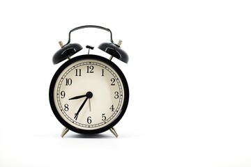 A black alarm clock with two bells on top, chrome handle, and legs, set against a white background....