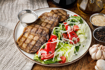 beef tongue with salad and sauce on a wooden background.