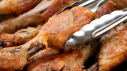Hand taking fried chicken legs with kitchen spatula for eating